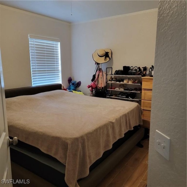 bedroom with ornamental molding and wood finished floors