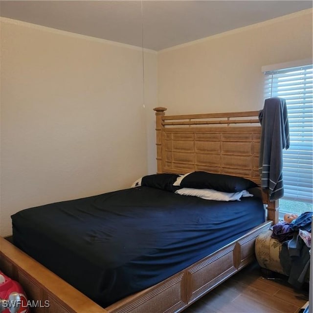bedroom with ornamental molding and wood finished floors
