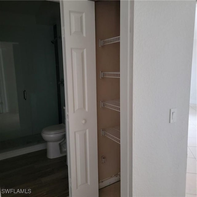 bathroom with a shower with shower door and toilet