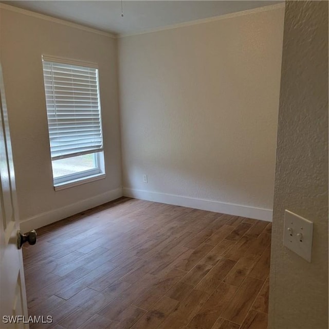 unfurnished room featuring ornamental molding, wood finished floors, and baseboards