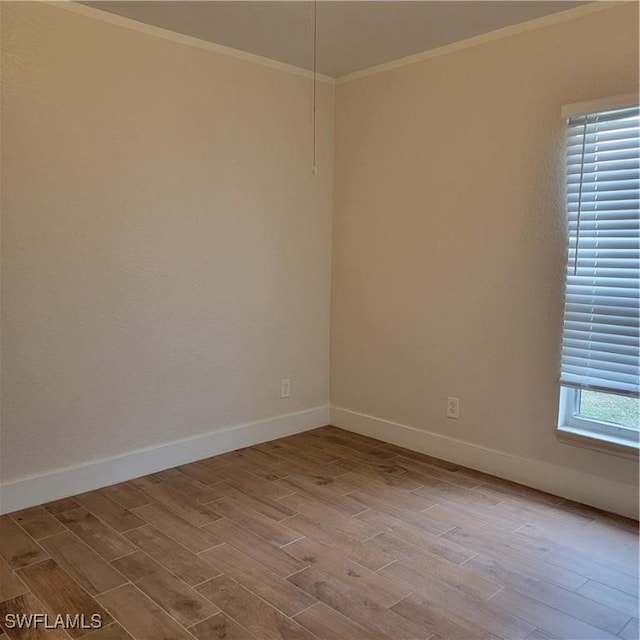 unfurnished room with crown molding, baseboards, and wood finished floors