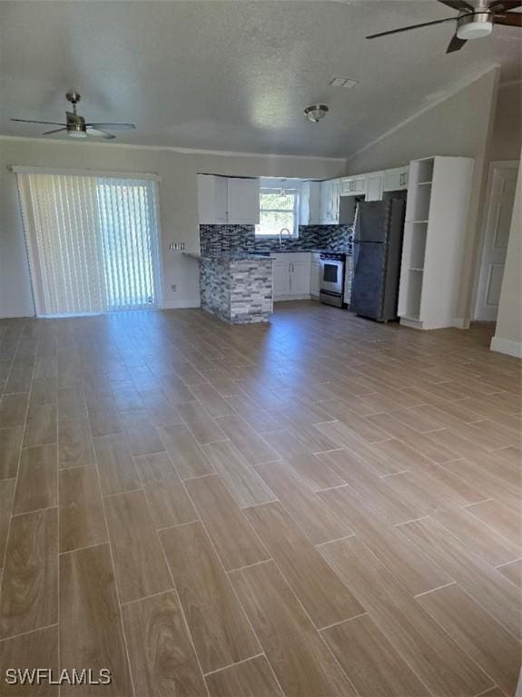 unfurnished living room featuring a ceiling fan, wood finish floors, and lofted ceiling