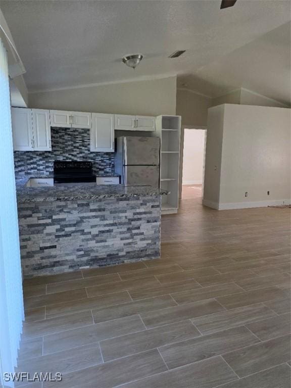 kitchen with lofted ceiling, visible vents, freestanding refrigerator, white cabinets, and black / electric stove