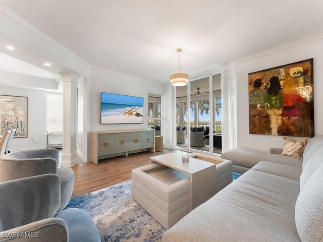 living room with light wood-type flooring, crown molding, and a wealth of natural light