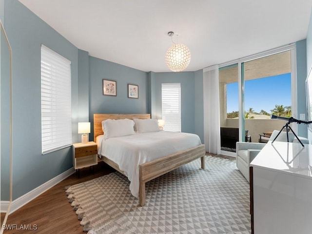 bedroom with hardwood / wood-style floors, access to exterior, and a chandelier