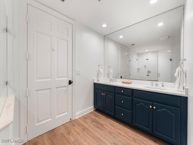 bathroom featuring vanity, wood-type flooring, and a shower with door