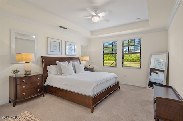 bedroom with ceiling fan, ornamental molding, light carpet, and a tray ceiling