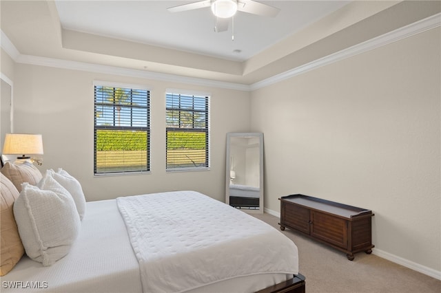 carpeted bedroom featuring a tray ceiling, ceiling fan, and ornamental molding