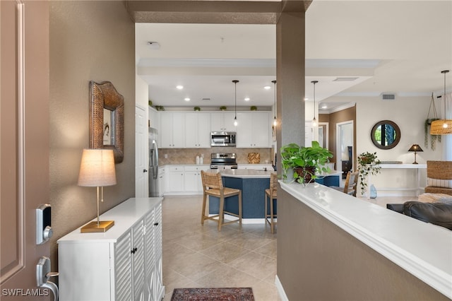 kitchen featuring white cabinets, decorative light fixtures, backsplash, and appliances with stainless steel finishes