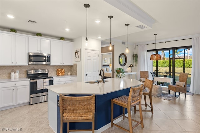 kitchen featuring white cabinetry, sink, stainless steel appliances, an island with sink, and pendant lighting