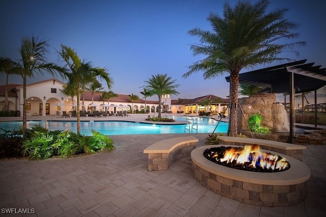 pool at dusk featuring an outdoor fire pit and a patio