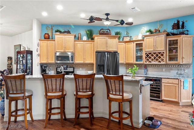 kitchen with decorative backsplash, light stone counters, light hardwood / wood-style floors, and appliances with stainless steel finishes