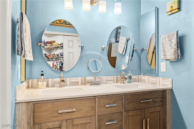 bathroom with double vanity, a sink, and a walk in closet