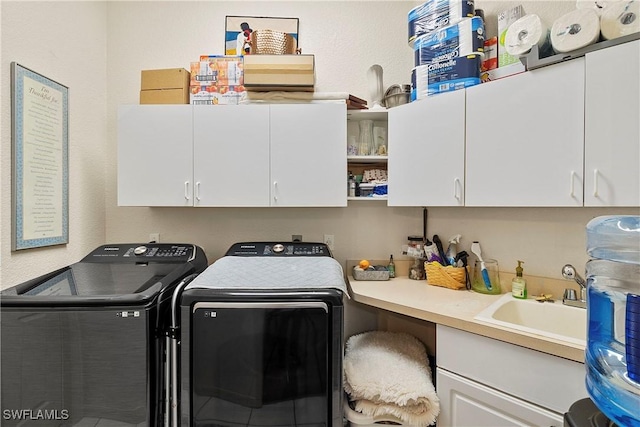 clothes washing area featuring independent washer and dryer, a sink, and cabinet space