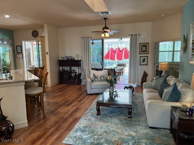 living room featuring wood finished floors, visible vents, and a ceiling fan