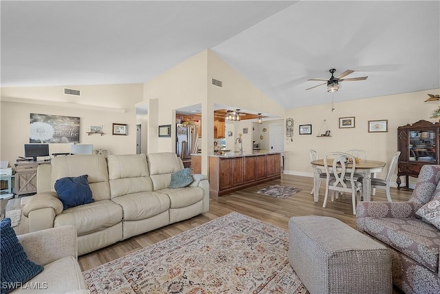 living room featuring ceiling fan, light wood-type flooring, sink, and high vaulted ceiling