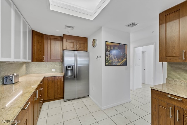 kitchen featuring decorative backsplash, stainless steel fridge, light tile patterned floors, and light stone countertops