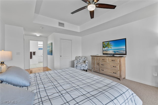 bedroom featuring a tray ceiling, ceiling fan, and light colored carpet