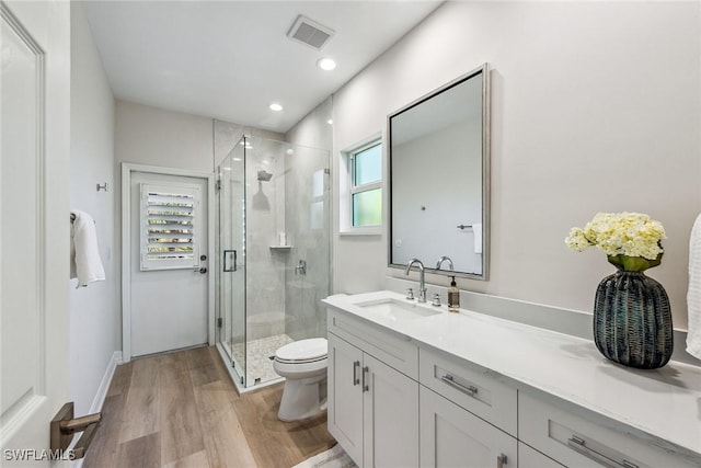 bathroom featuring vanity, hardwood / wood-style floors, walk in shower, and toilet