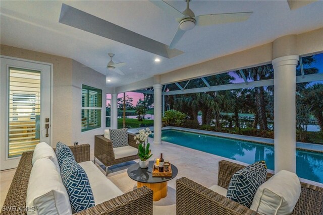 pool at dusk featuring a patio area, ceiling fan, and an outdoor hangout area