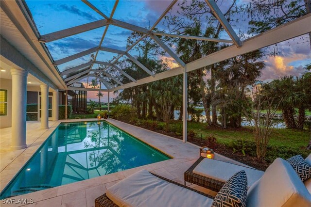 pool at dusk featuring a lanai and a patio area