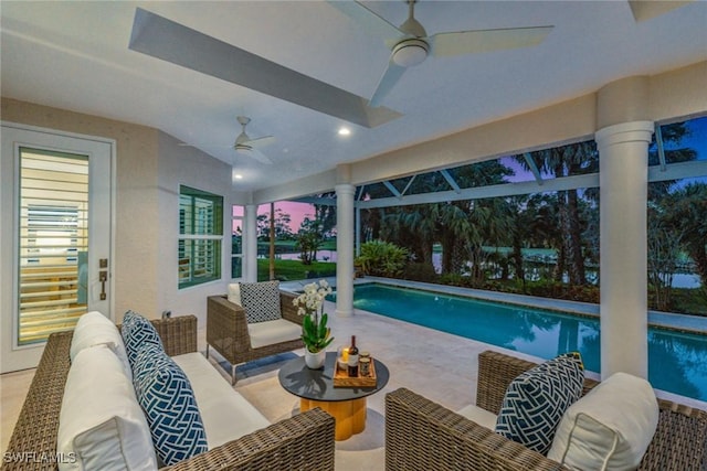 pool at dusk with ceiling fan, outdoor lounge area, and a patio