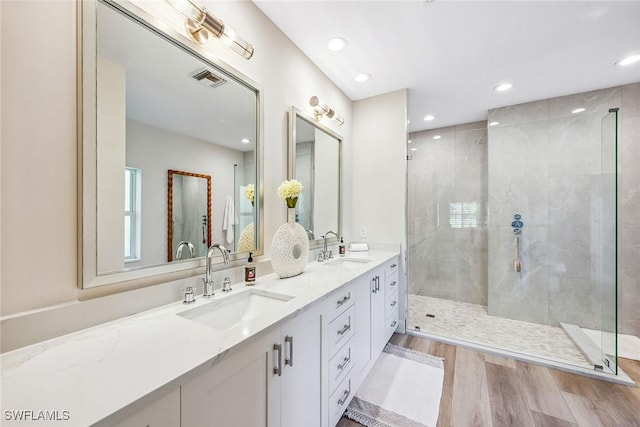 bathroom with a tile shower, vanity, and hardwood / wood-style flooring