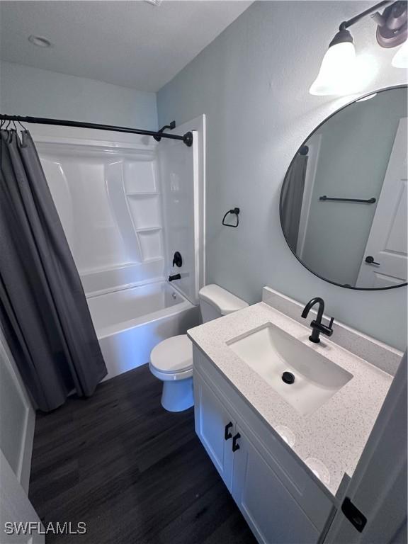 full bathroom with hardwood / wood-style floors, vanity, toilet, and shower / bath combo with shower curtain