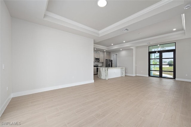 unfurnished living room with french doors, light wood-type flooring, ornamental molding, and a tray ceiling