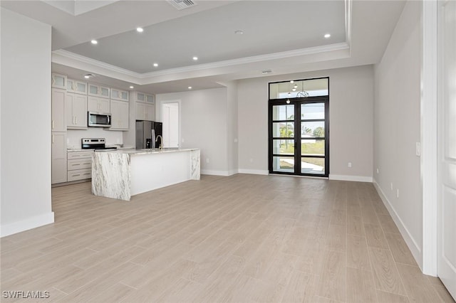 kitchen featuring white cabinetry, stainless steel appliances, light hardwood / wood-style floors, a center island with sink, and ornamental molding