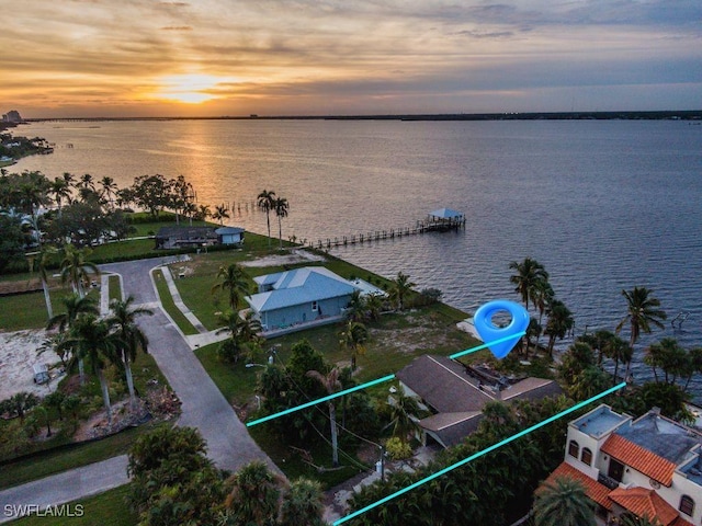 aerial view at dusk featuring a water view