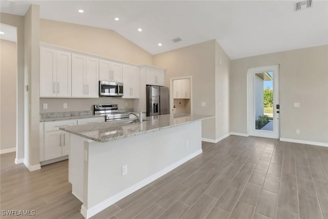 kitchen with stainless steel appliances, white cabinetry, and a center island with sink