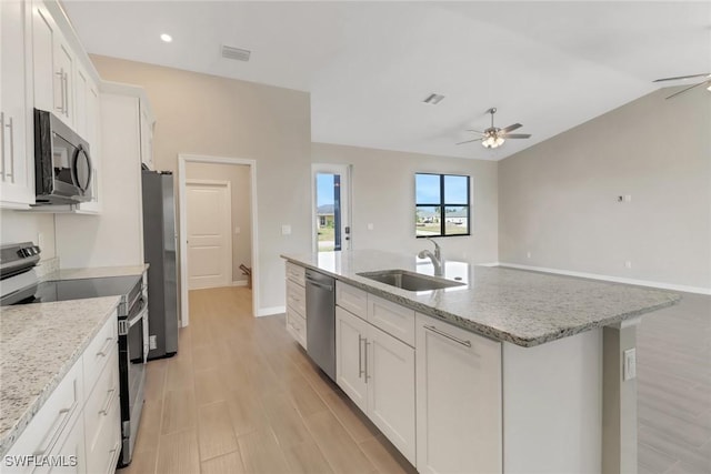 kitchen featuring stainless steel appliances, white cabinetry, a kitchen island with sink, and sink