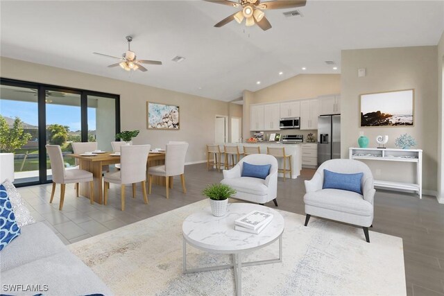 living room with ceiling fan, light hardwood / wood-style floors, and vaulted ceiling