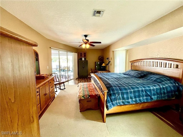 bedroom featuring access to exterior, a textured ceiling, light colored carpet, and ceiling fan