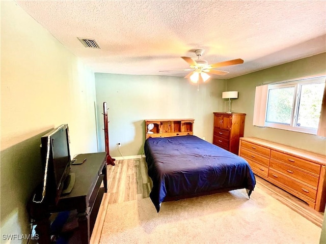 bedroom featuring ceiling fan, a textured ceiling, and light wood-type flooring