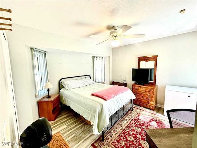 bedroom with ceiling fan, light hardwood / wood-style floors, and a textured ceiling