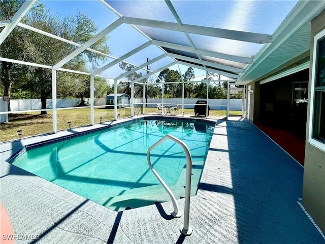 view of swimming pool with a patio, a shed, glass enclosure, and a lawn