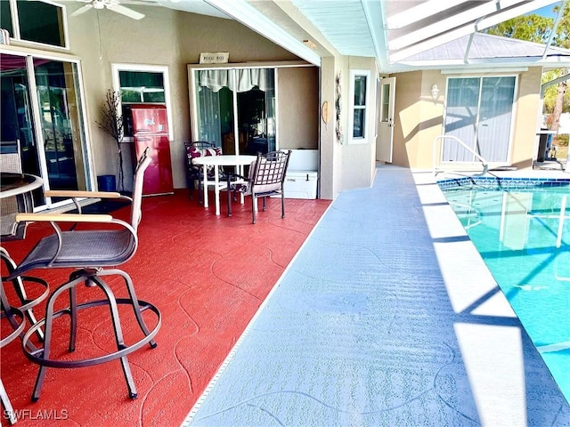 view of pool with glass enclosure, ceiling fan, and a patio