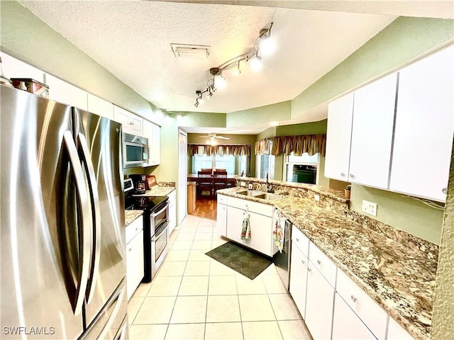 kitchen featuring white cabinets, sink, ceiling fan, a textured ceiling, and appliances with stainless steel finishes