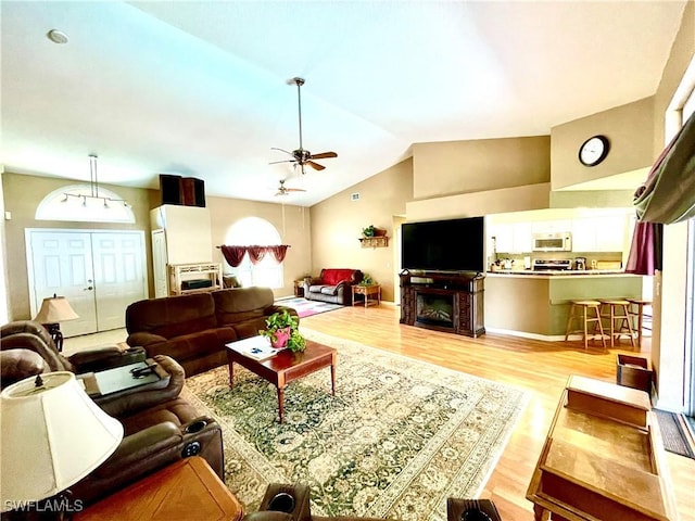 living room featuring ceiling fan, light hardwood / wood-style flooring, and vaulted ceiling