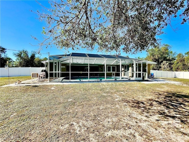 back of property featuring a fenced in pool, glass enclosure, and a lawn