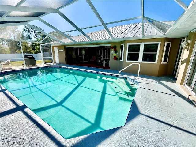 view of pool with glass enclosure and a patio area