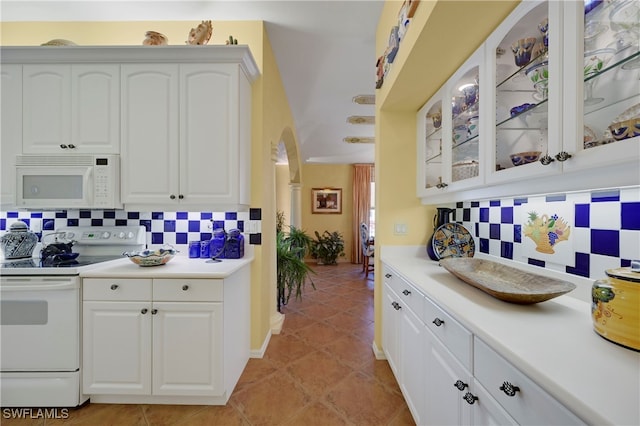10801 Crooked River Rd Unit 203, Estero, FL 34135 - kitchen with white appliances, tasteful backsplash, glass insert cabinets, light countertops, and white cabinetry
