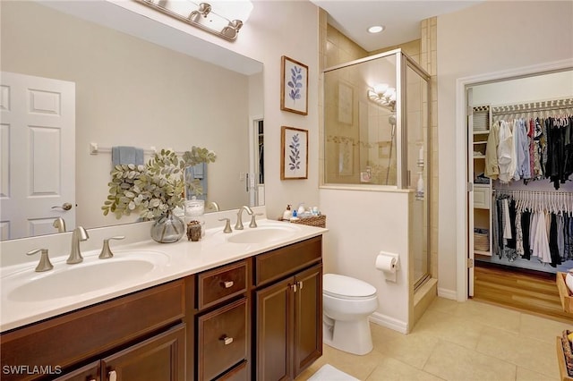 bathroom with tile patterned floors, vanity, toilet, and a shower with door