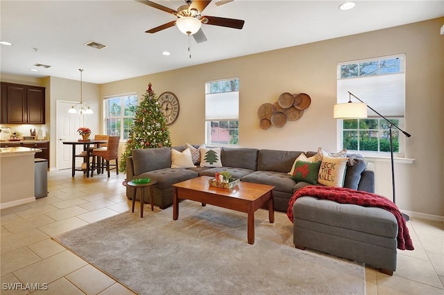 tiled living room featuring ceiling fan with notable chandelier