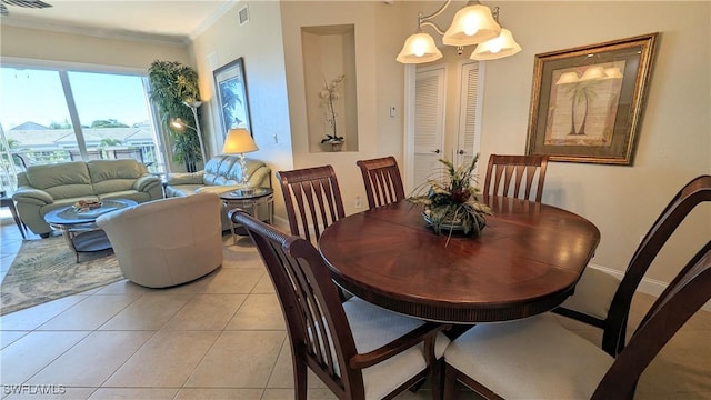 tiled dining area featuring a notable chandelier and ornamental molding