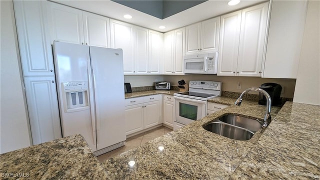 kitchen featuring sink, light tile patterned floors, dark stone countertops, white appliances, and white cabinets