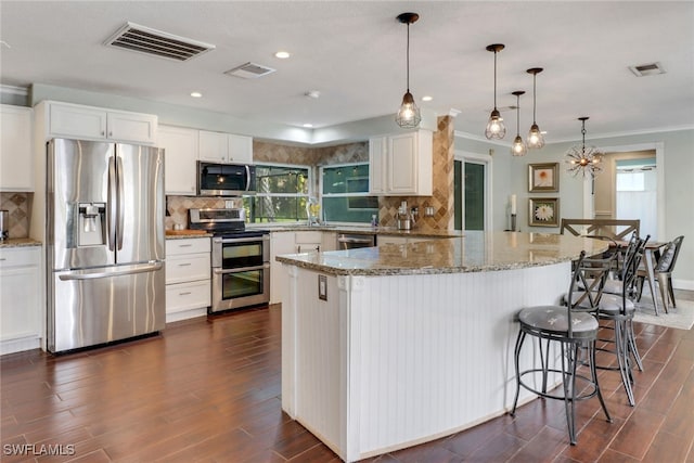 kitchen featuring light stone counters, decorative light fixtures, decorative backsplash, white cabinets, and appliances with stainless steel finishes