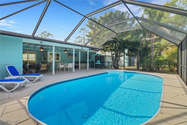 view of pool with a patio area, ceiling fan, and glass enclosure